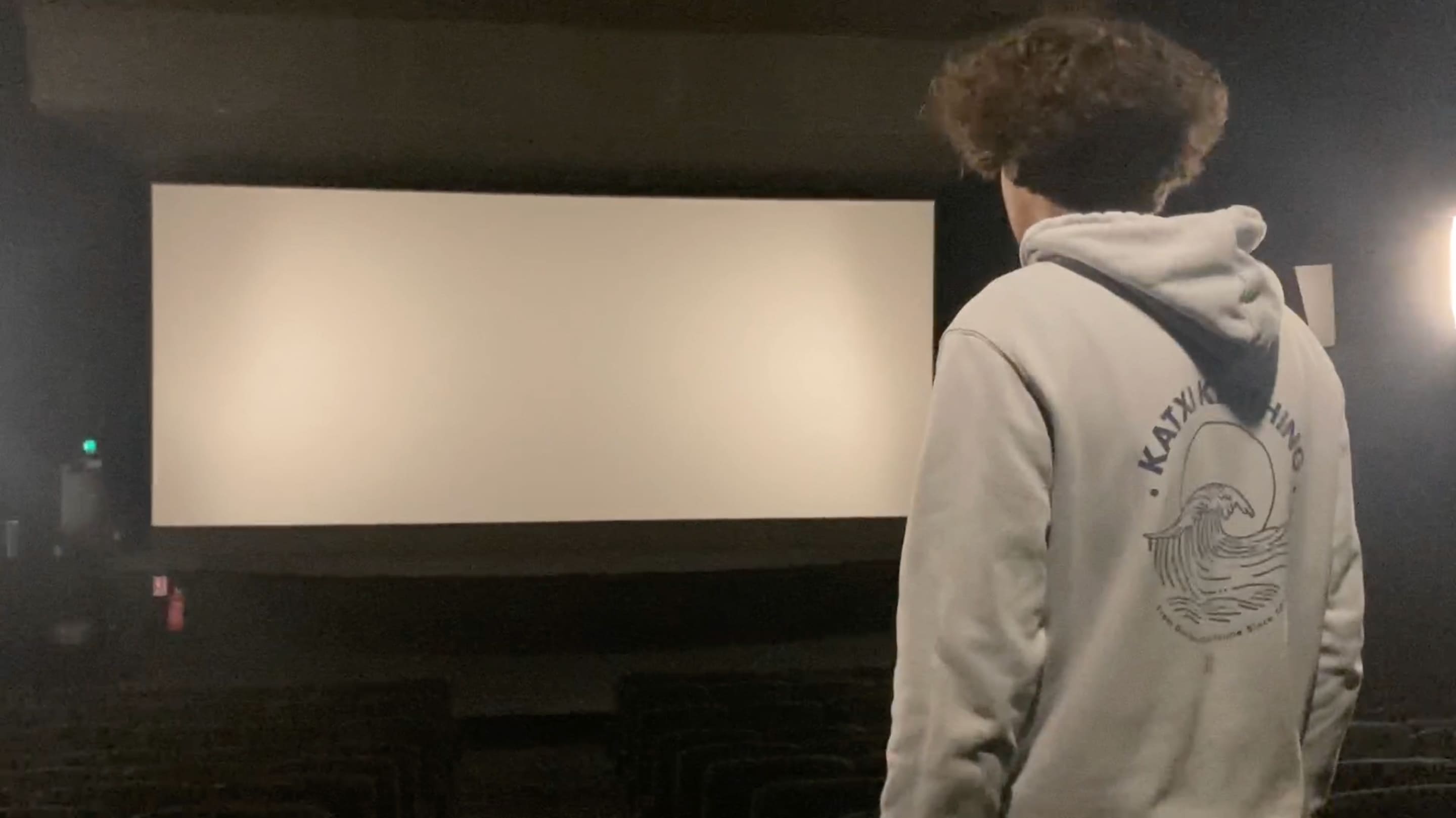 Image tirée de Eye of the Creator où un homme se trouve dans une salle de cinéma et regarde l’immense écran blanc.